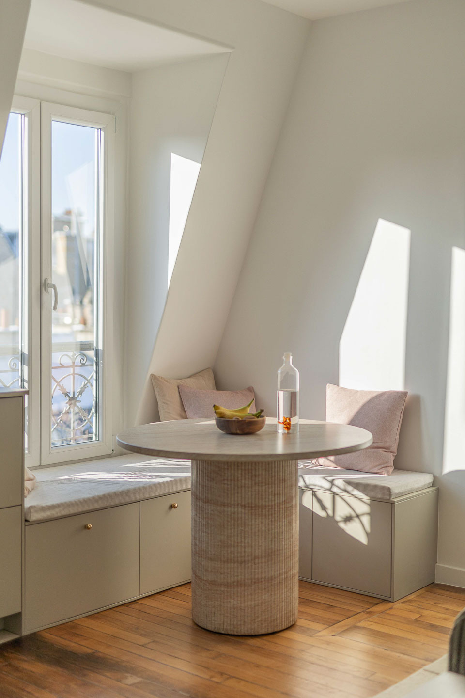 Coin repas : table en travertin et banquettes sous la fenêtre